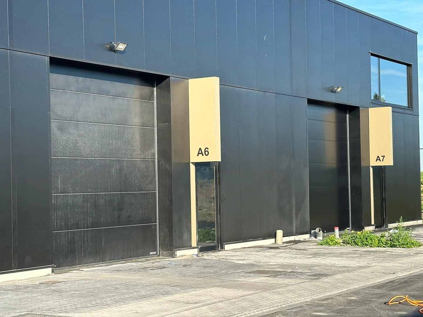 Reiniging van vrachtwagenpoorten aan bedrijfsgebouw in regio Antwerpen