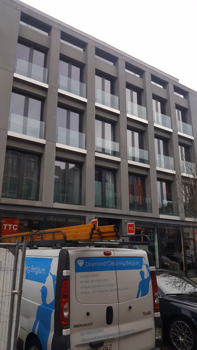Ramenwasser met hoogtewerker voert glasreiniging uit bij gebouw in Merksem