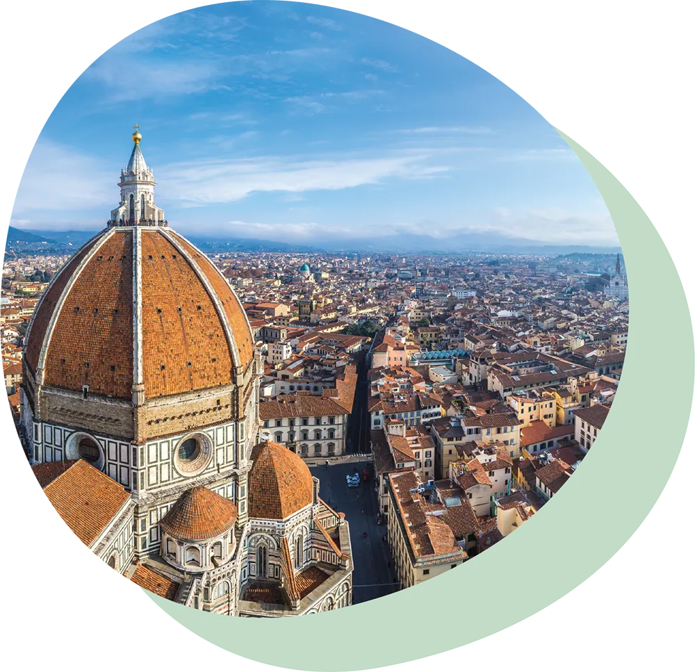 Aerial view of Florence, Italy, featuring the red-tiled dome of the Florence Cathedral against a blue sky.