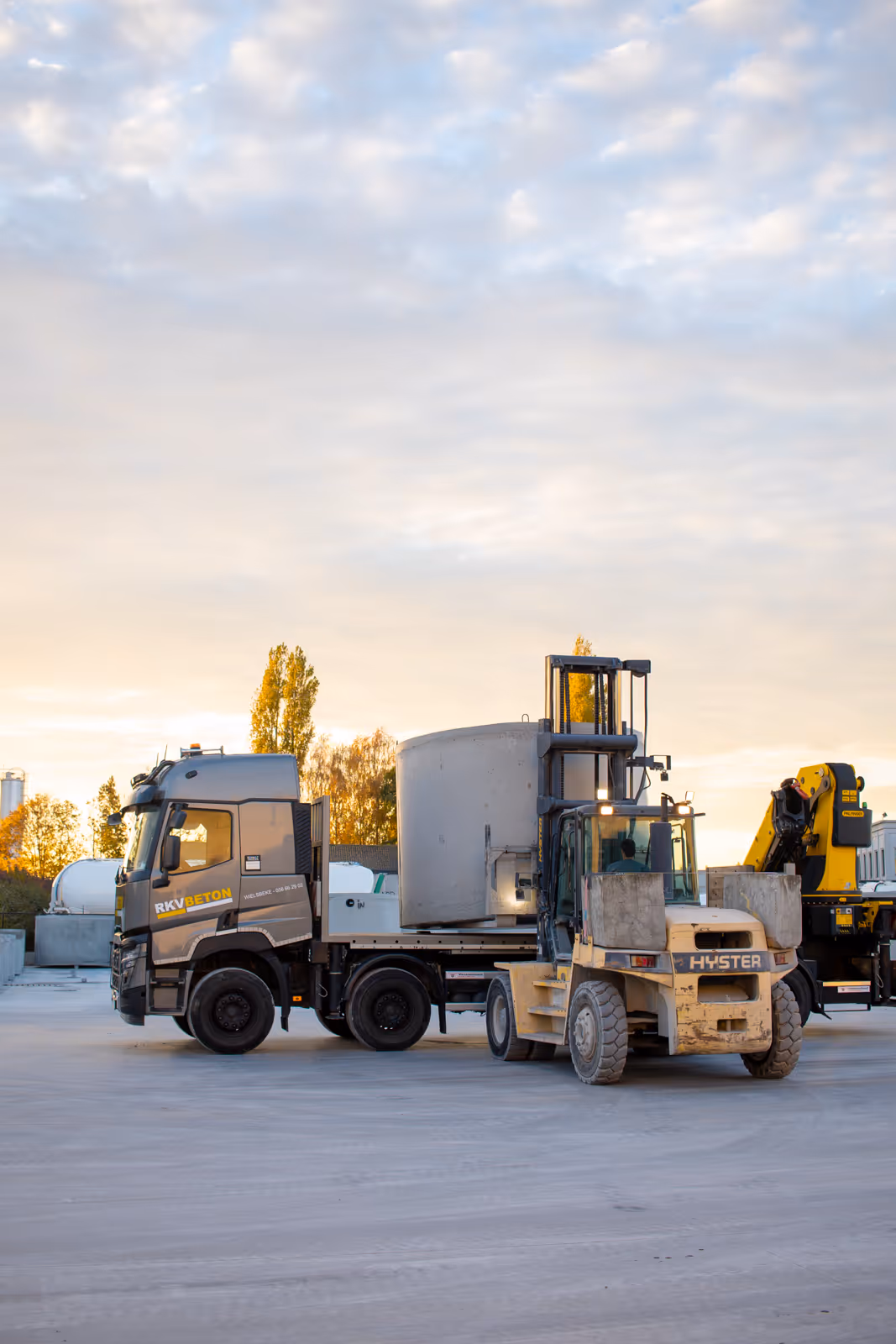 Vrachtwagen met heftruck op betonwerf, klaar voor levering van prefab betonputten