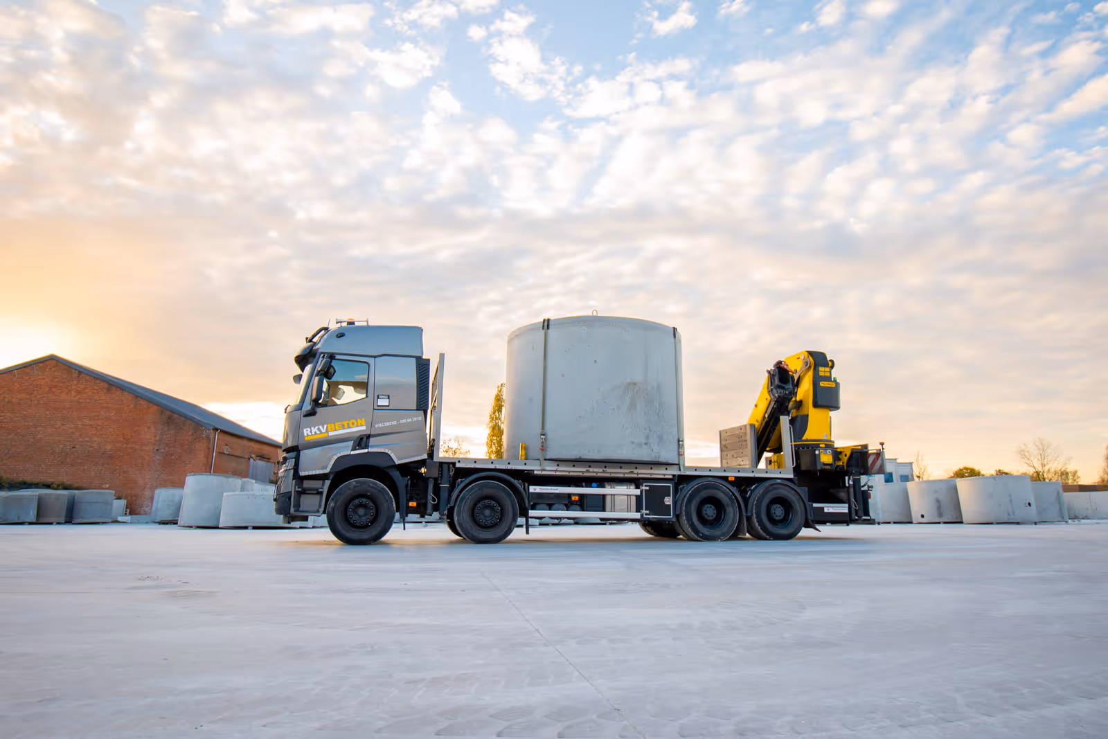 Kraan laadt betonnen put op vrachtwagen voor levering op locatie