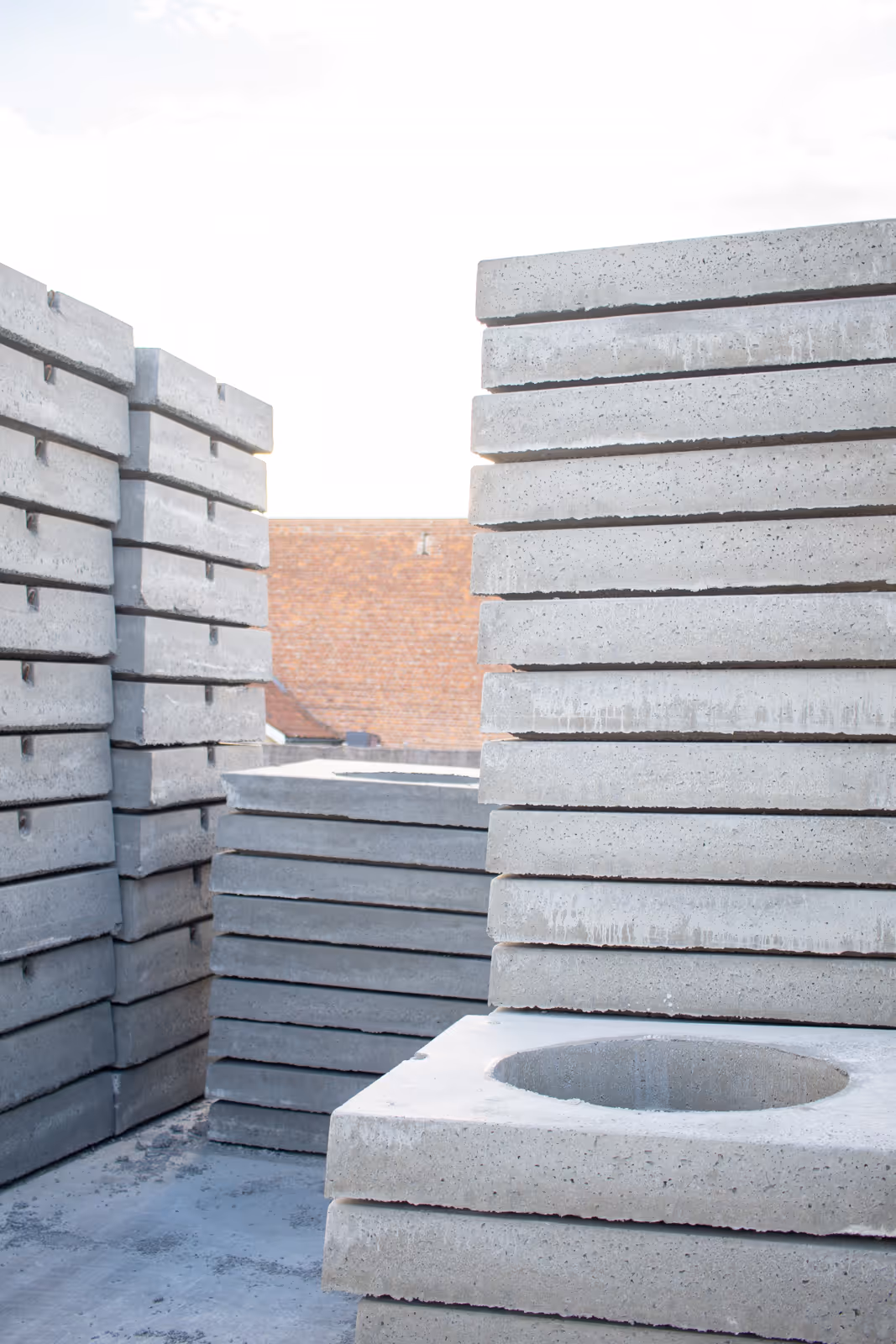 Dekplaat in gewapend beton, met vierkante mangatopening en ingegoten gietijzeren deksel, klaar voor plaatsing op regenput