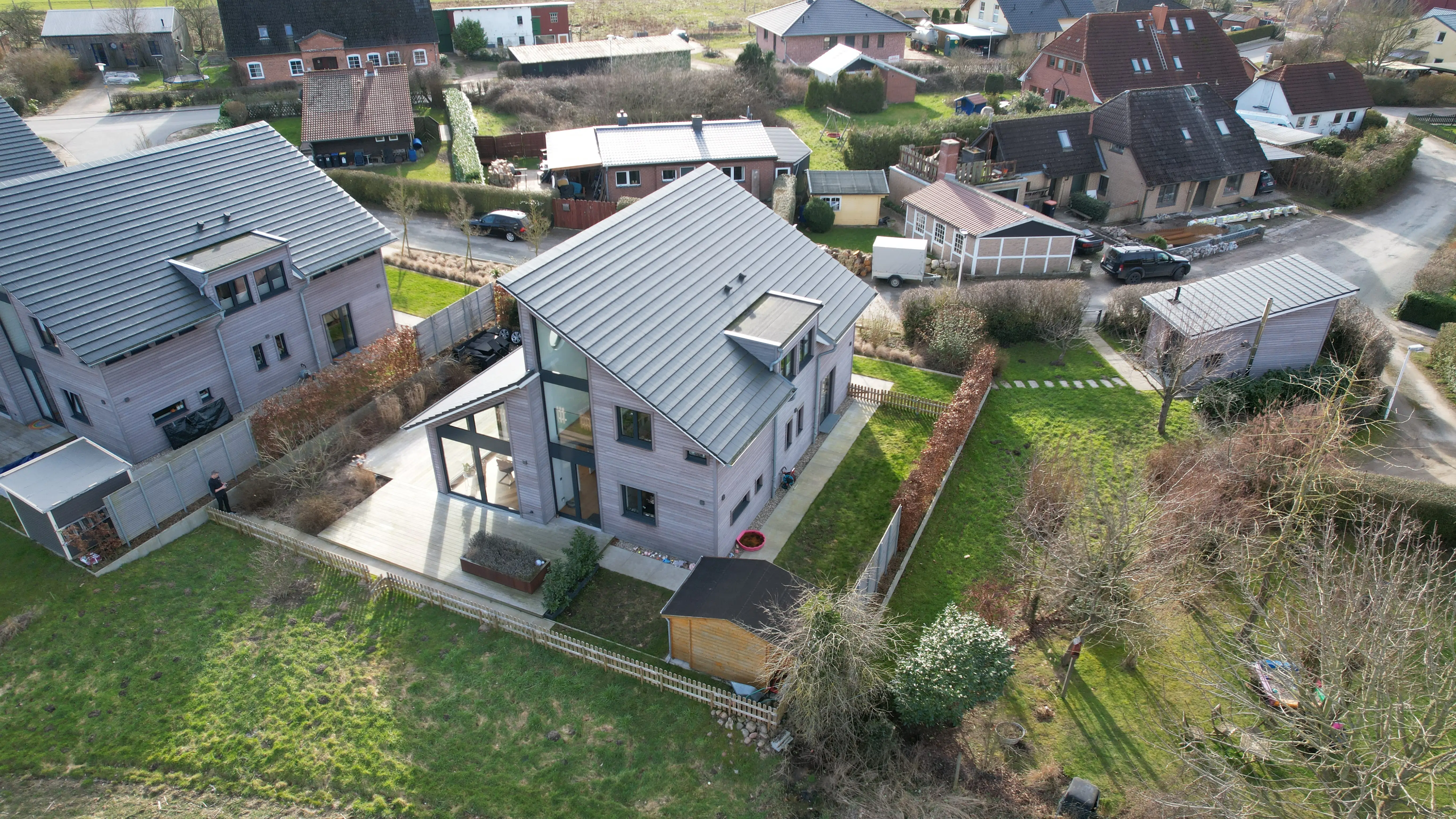 Luftaufnahme eines modernen Hauses mit großem Garten und Nebengebäude in einem Wohngebiet.