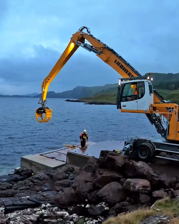 A tractor carrying stones in front of the sea