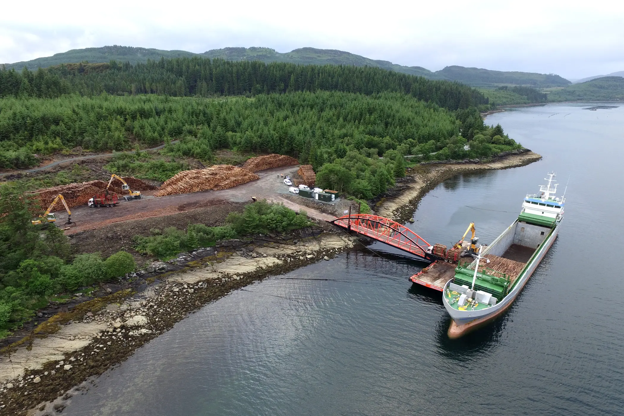 A large boat is on a body of water in front of a bridge.