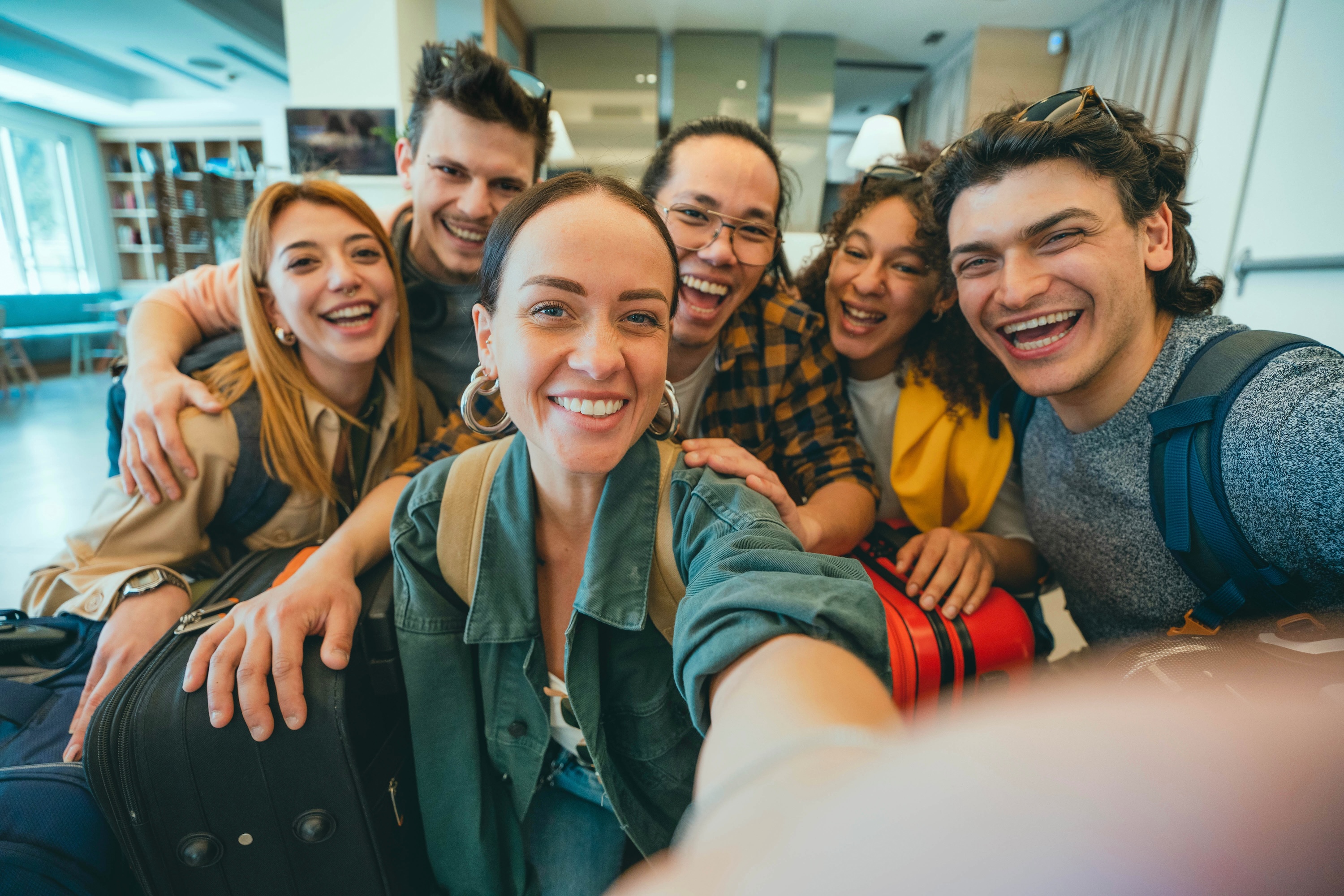 A group of smiling students taking a selfie in a lobby surrounded by luggage, representing the welcoming and social community at ArtHaus Dwight in Berkeley, CA.