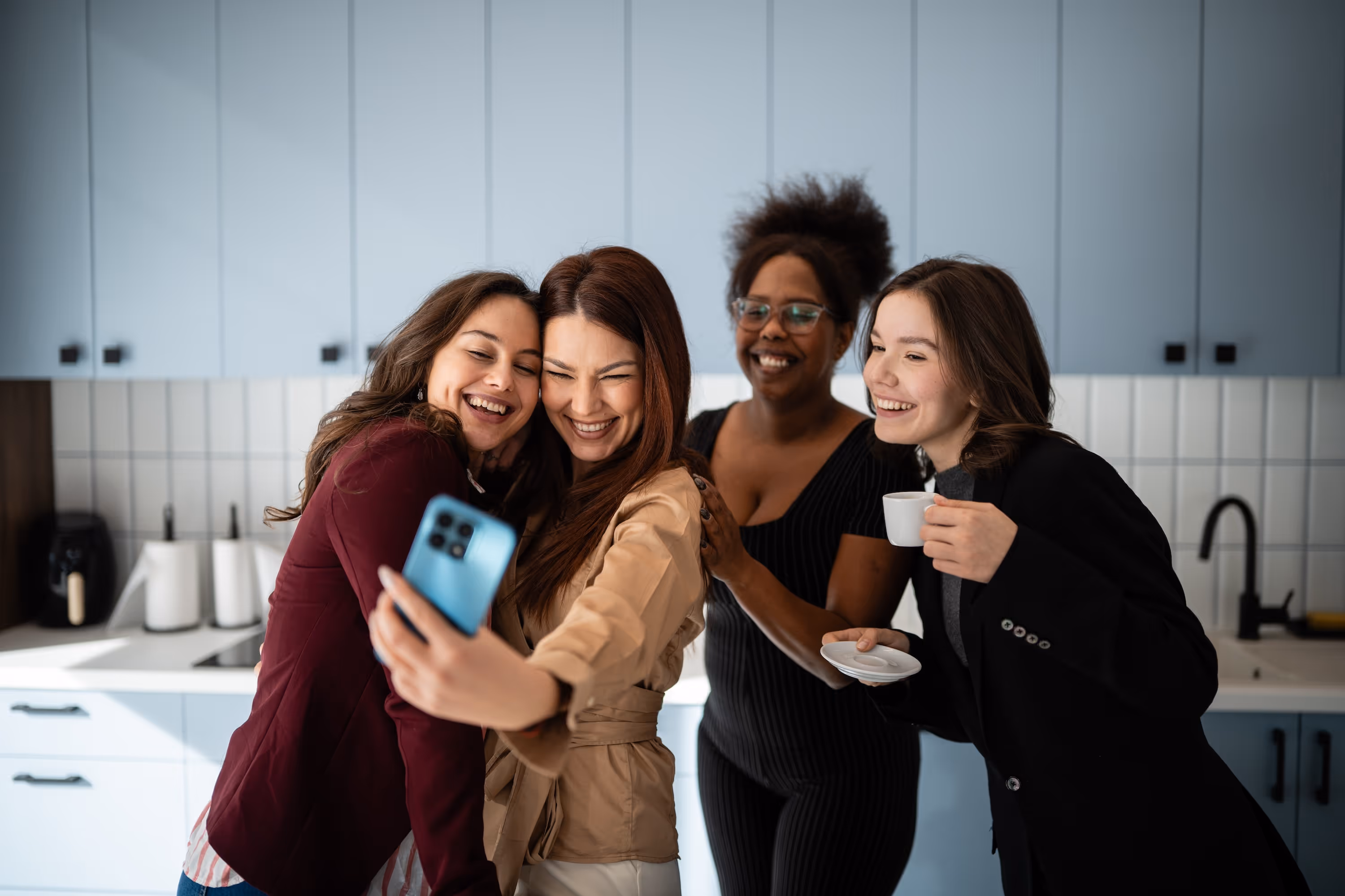 Friends taking a selfie and enjoying coffee in the bright, shared resident lounge at ArtHaus Dwight urban housing