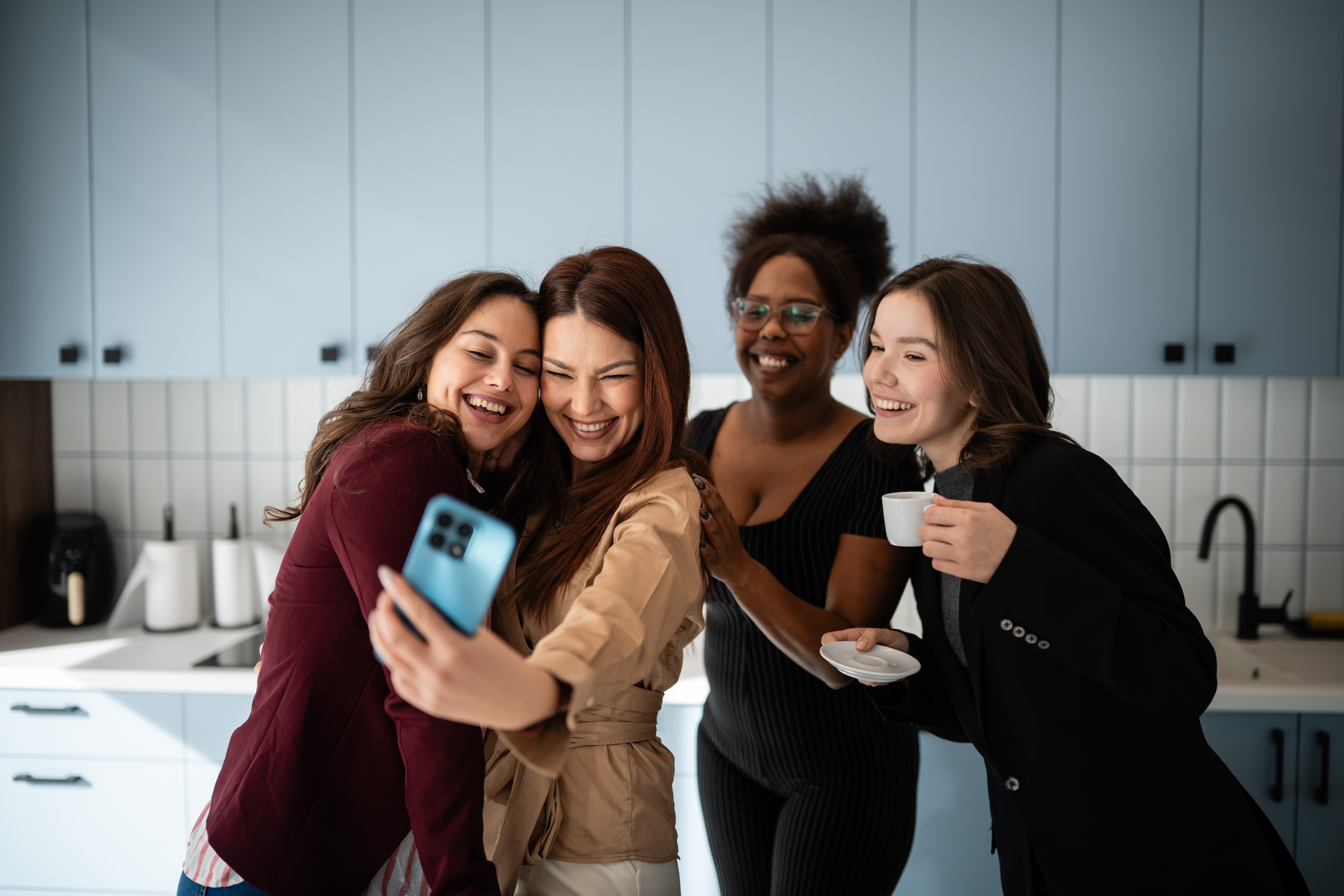 Friends taking a selfie and enjoying coffee in the bright, shared resident lounge at ArtHaus Dwight urban housing