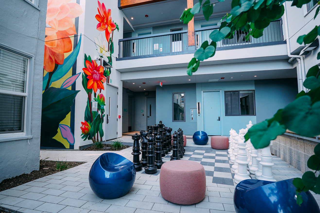 An elevated view of the landscaped central courtyard, showing the paved patio, a table with chairs, comfortable seating, and tall bamboo plants flanking the edges.