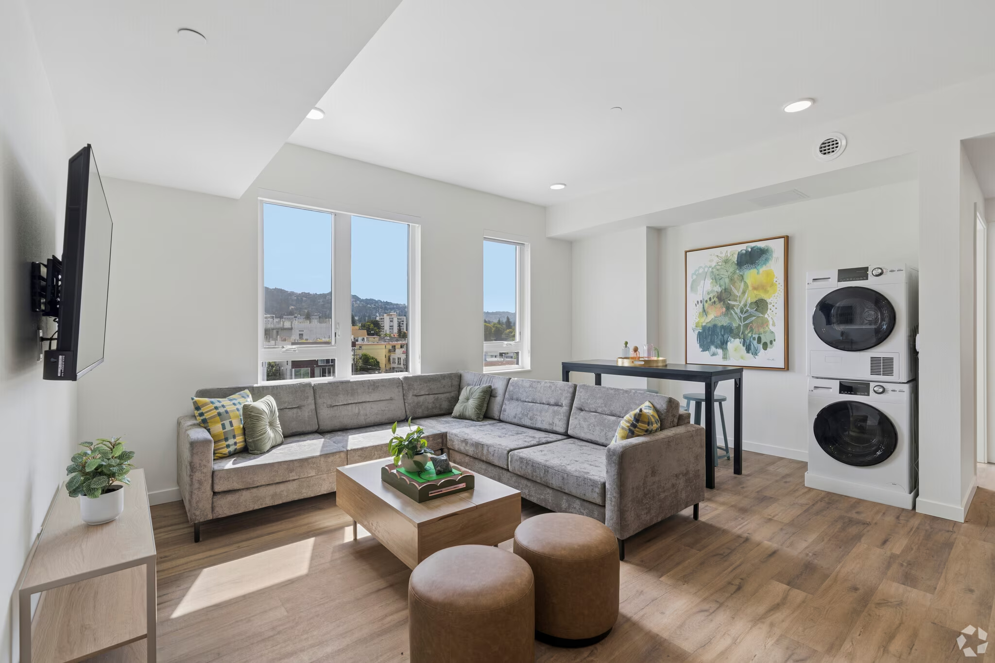 Apartment living room and kitchen featuring a purple sofa, wood coffee table, and open-concept layout with stainless steel appliances at ArtHaus Dwight in Berkeley, CA.