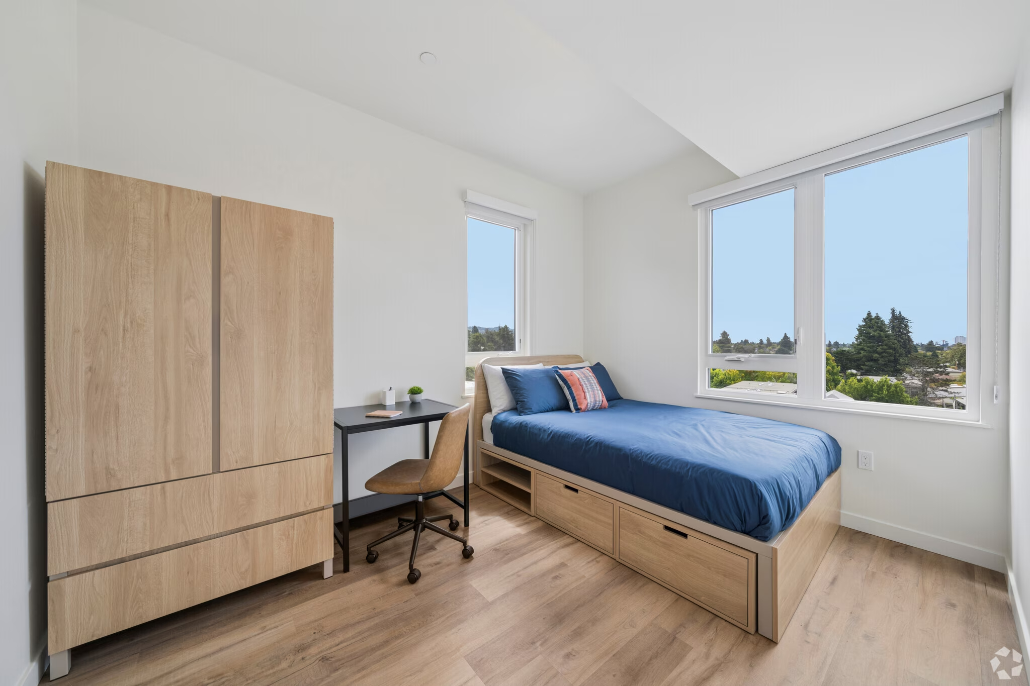 Fully furnished apartment bedroom featuring a bed, a dedicated desk area, and large windows at ArtHaus Dwight in Berkeley, CA.