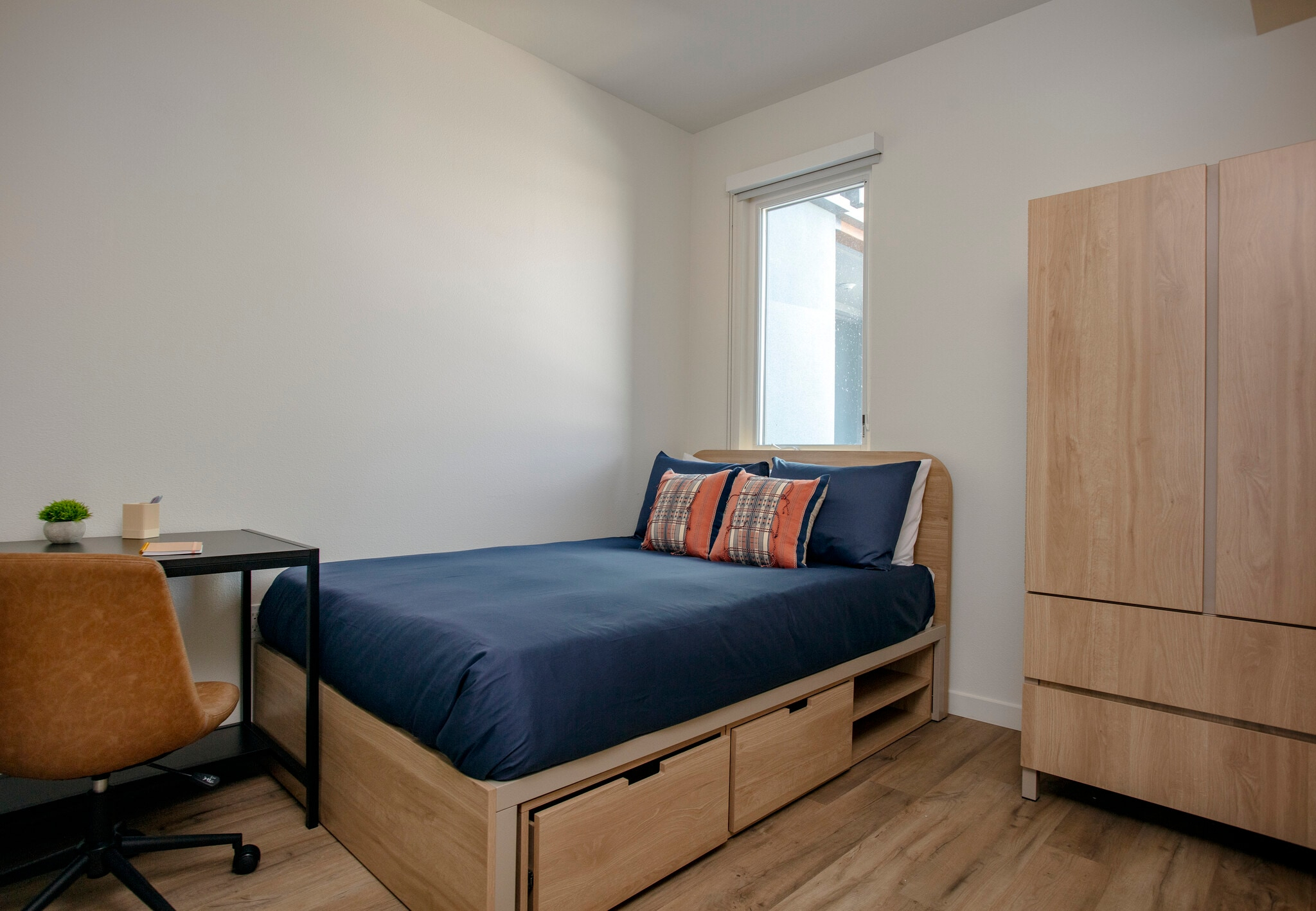View from hallway at two bedrooms fully furnished featuring a bed, a dedicated desk area, and large windows at ArtHaus Dwight in Berkeley, CA.