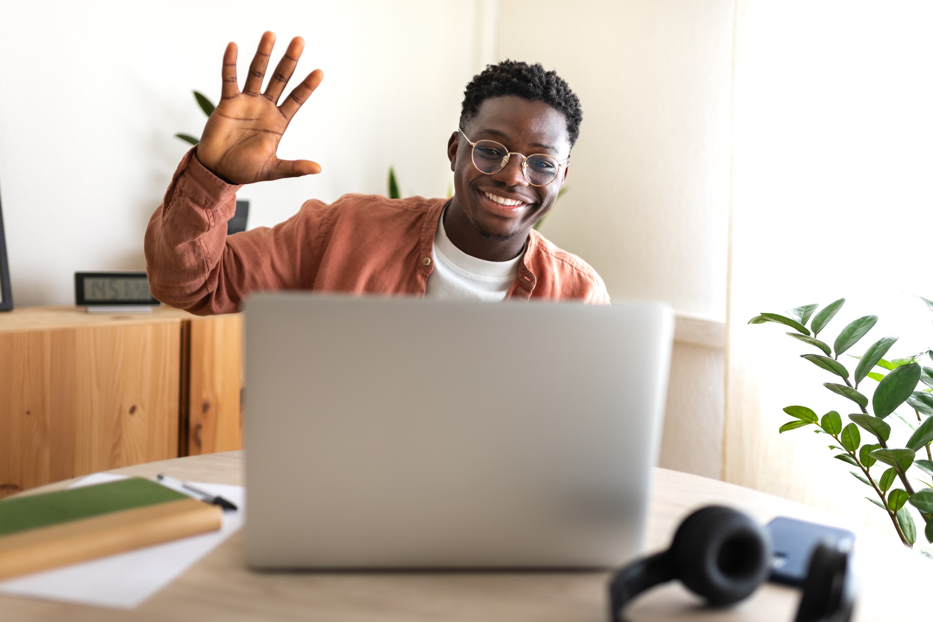 Resident waving during a video call on a laptop inside an apartment at ArtHaus Dwight in Berkeley, CA