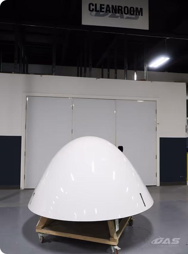 Large smooth white dome-shaped object on a wooden cart with wheels in an industria area.
