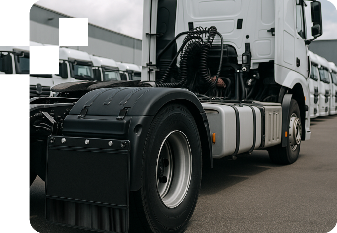 Close-up of the rear side of a white semi-truck tractor with other trucks lined up in the background.