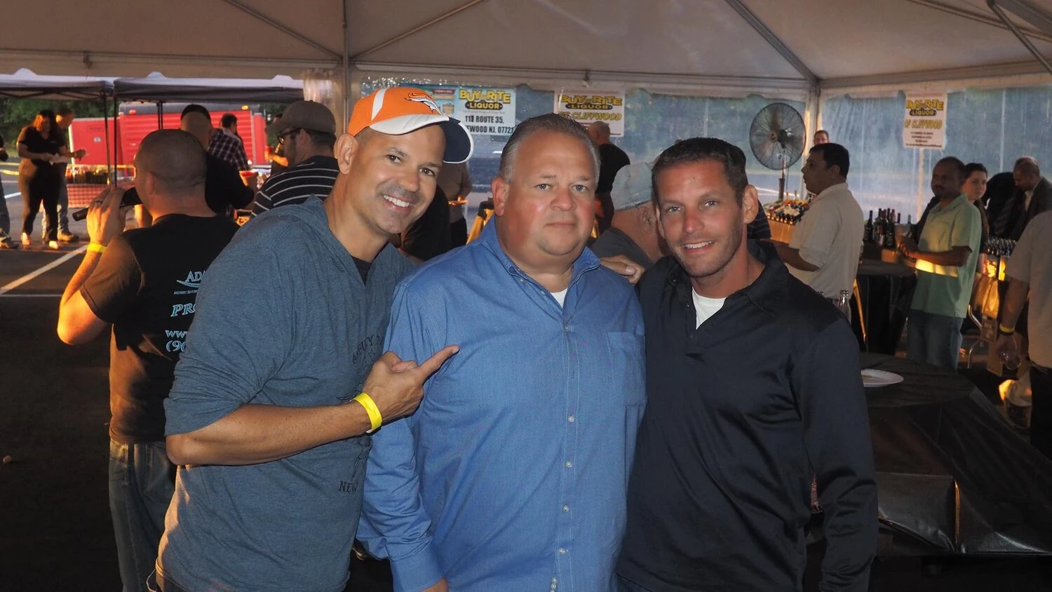 3 men take a photo under a tent