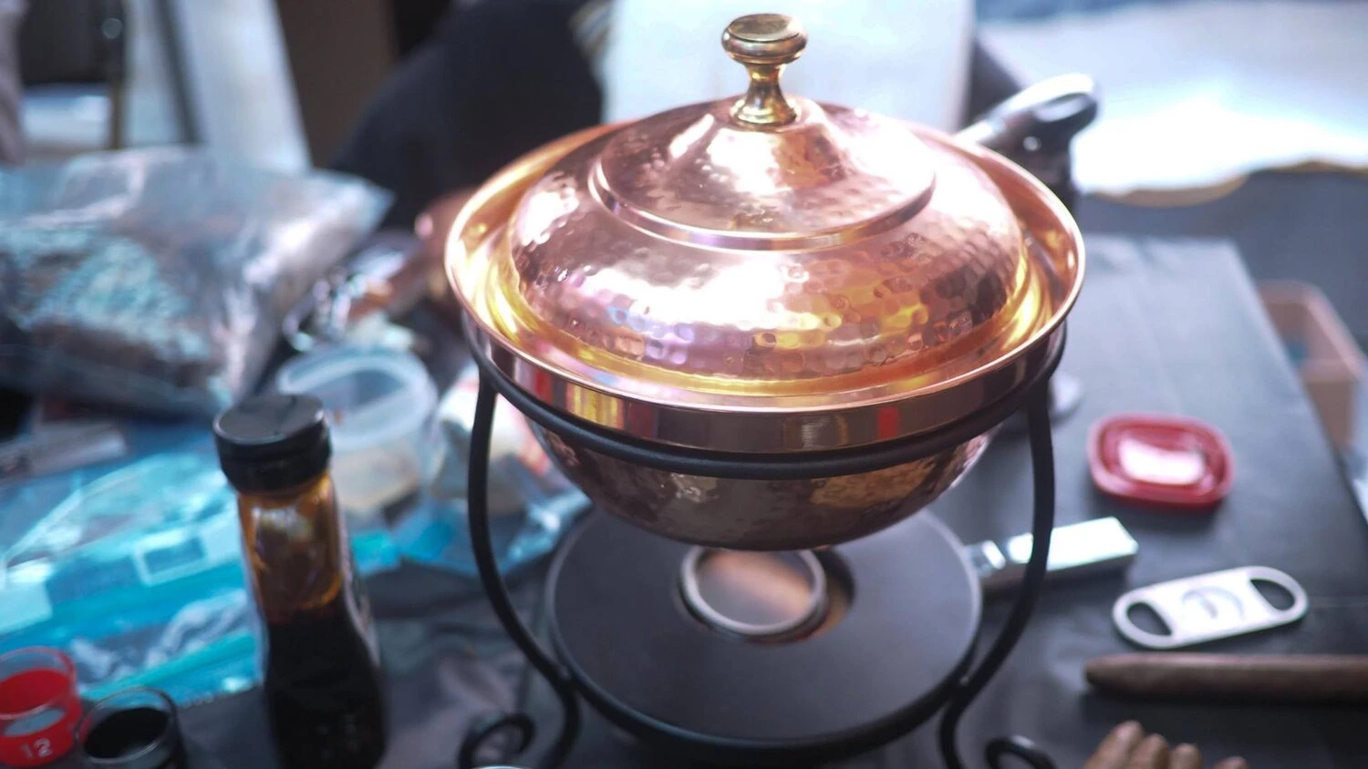 a copper dish sitting on a table surrounded by cigar related items
