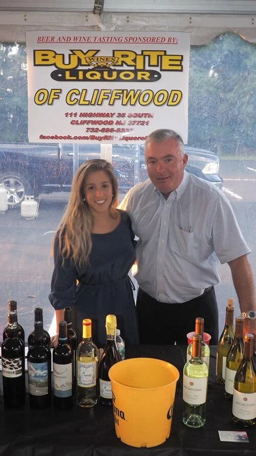 two people standing behind a wine tasting table