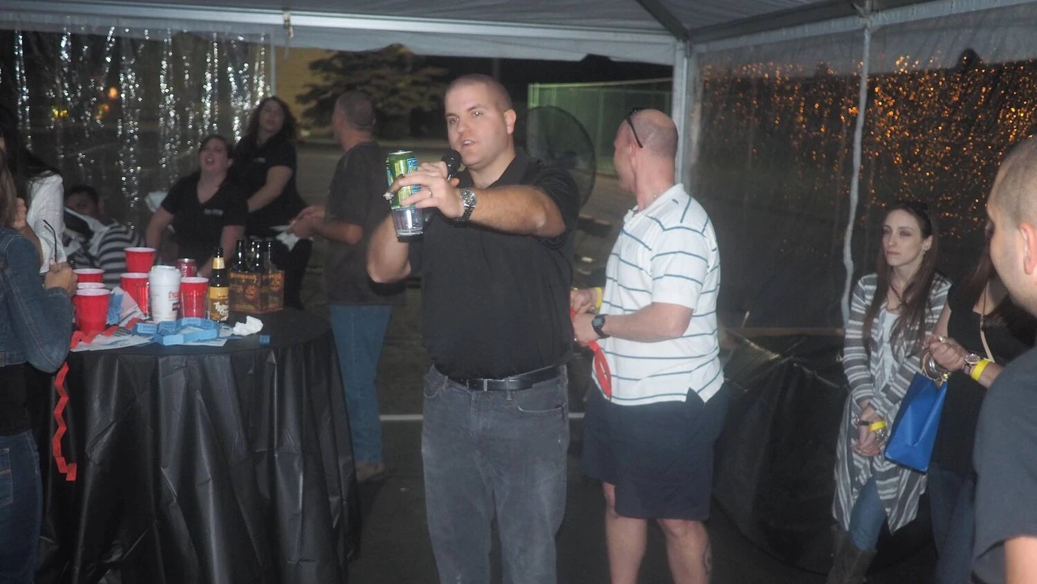 a person with a drink in his hand speaks into a microphone