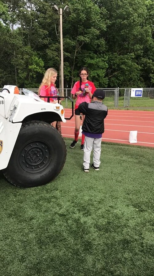 3 people standing by a police vehicle