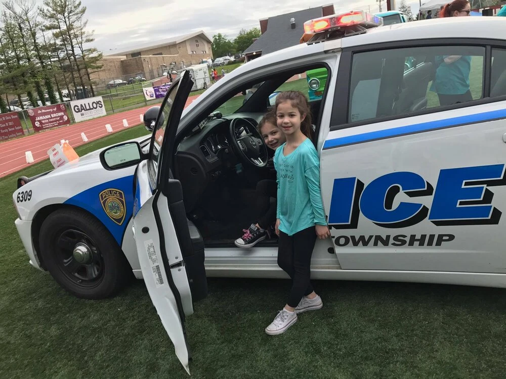a child standing in the doorway of a police car