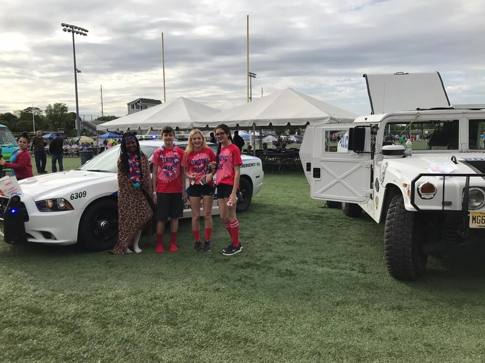 a group taking a photo by two police vehicles