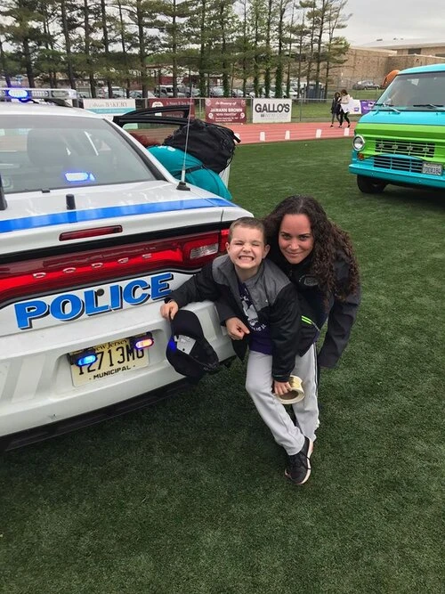 a woman a child standing behind a police car
