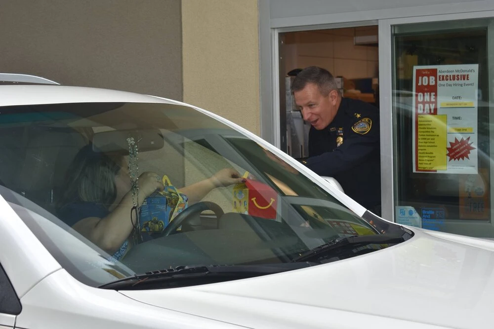 a police officer in the drive thru window giving food to customer