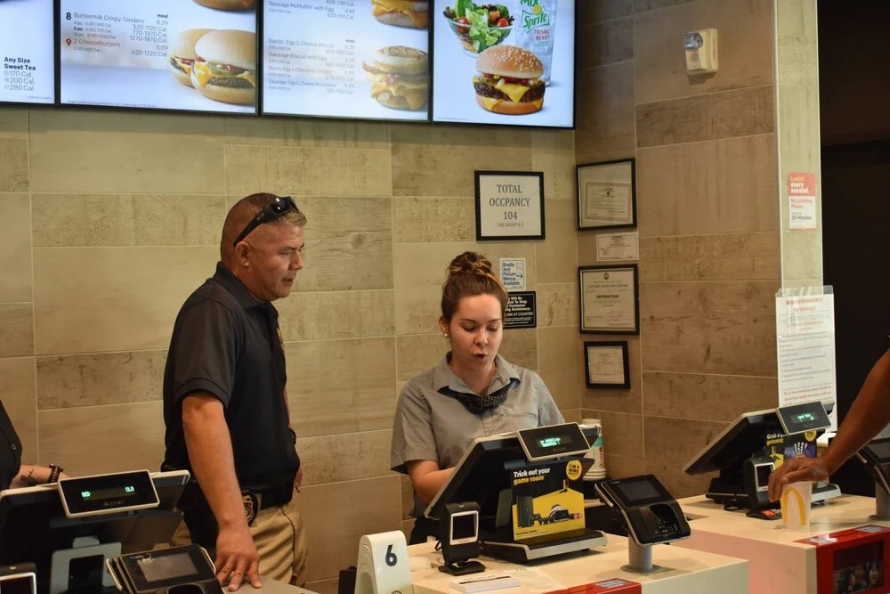 an officer watching a cashier show him the register