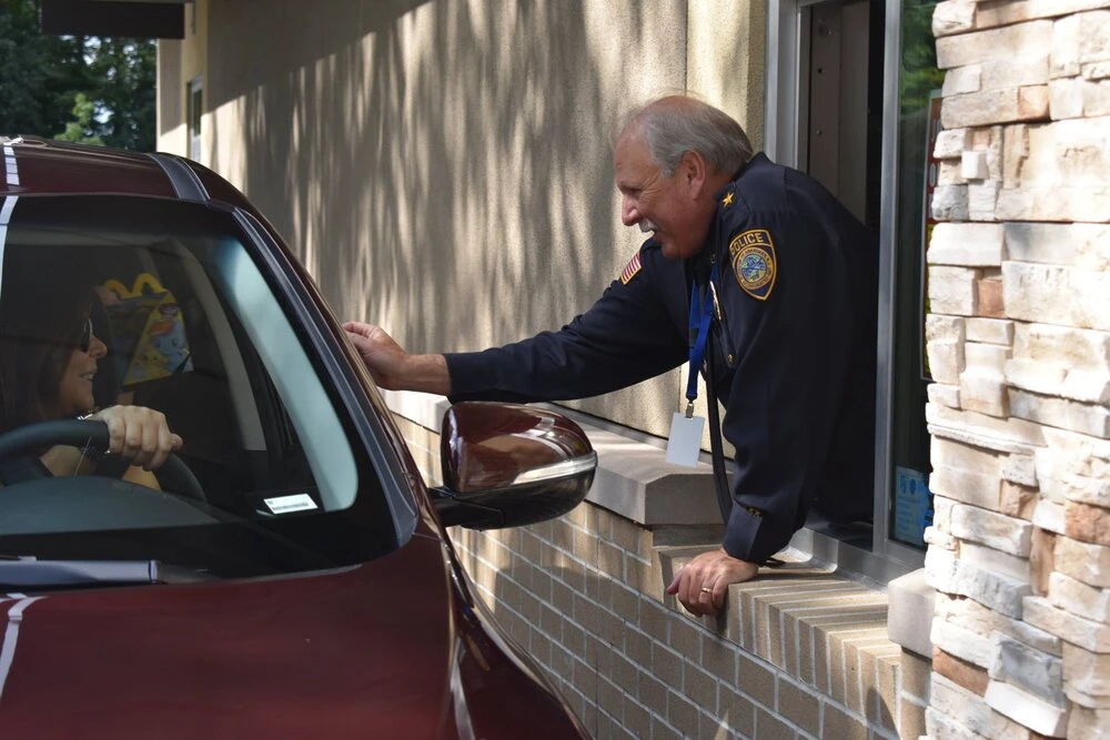 a police officer in the drive thru window giving food to customer
