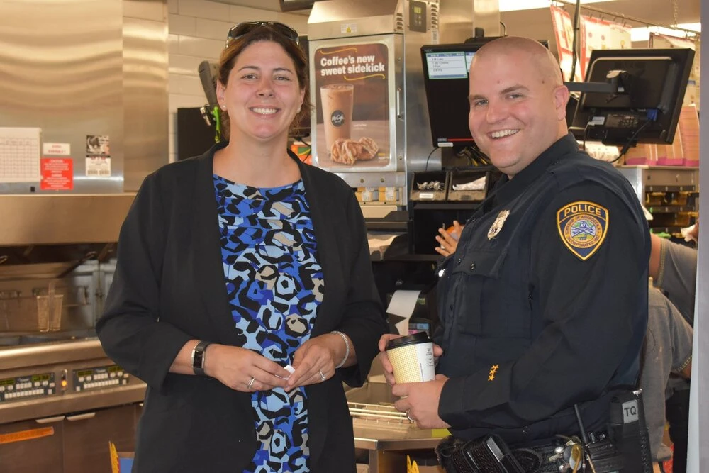 a woman stands next to an officer smiling