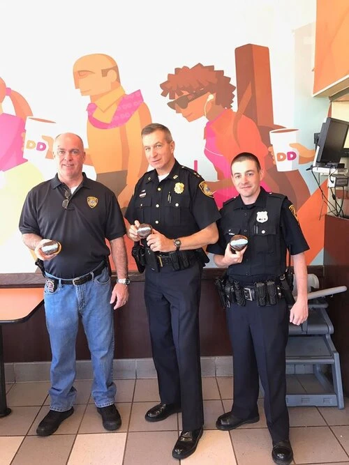 two officers take a photo with a coffee shop patron