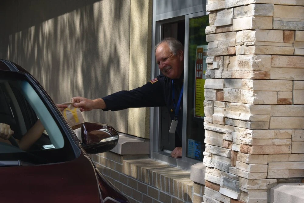 a police officer in the drive thru window giving food to a customer