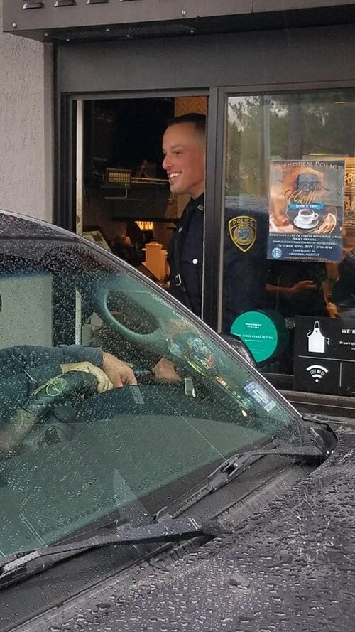an officers gives coffee to a customer in their car