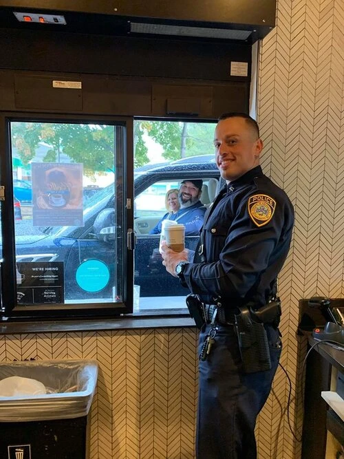 police officer in the drive through window holding a cup of coffee