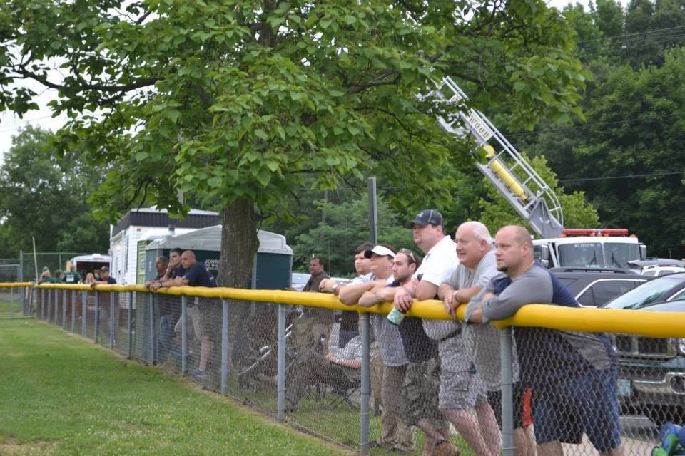a group of people leaning on railing at a baseball game