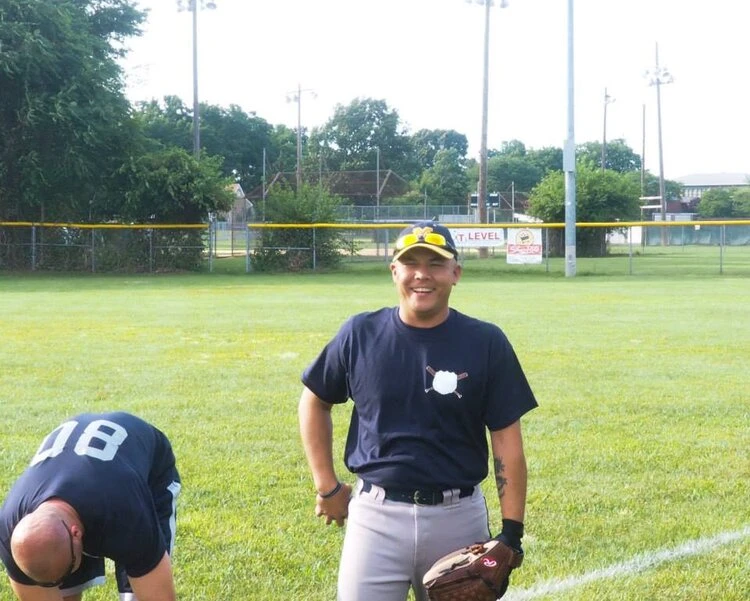 one person standing with a baseball glove next to another person bent over