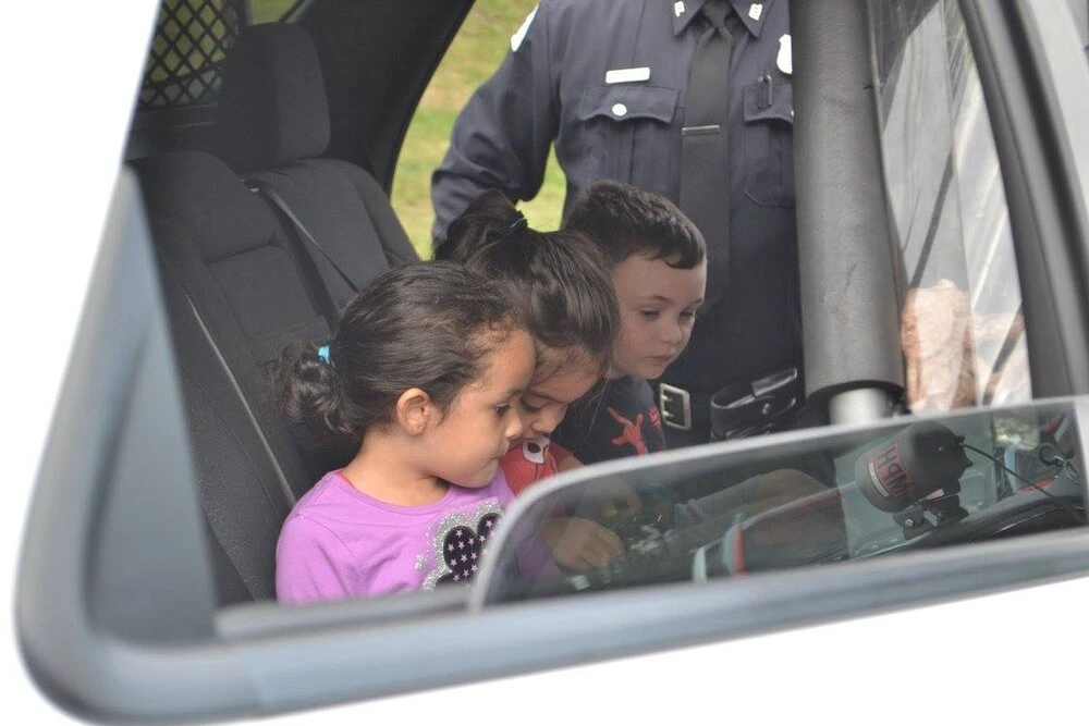 3 children sitting in a police car
