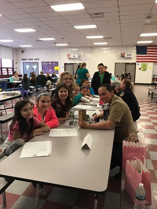 children sit with a police officer at a lunch room table