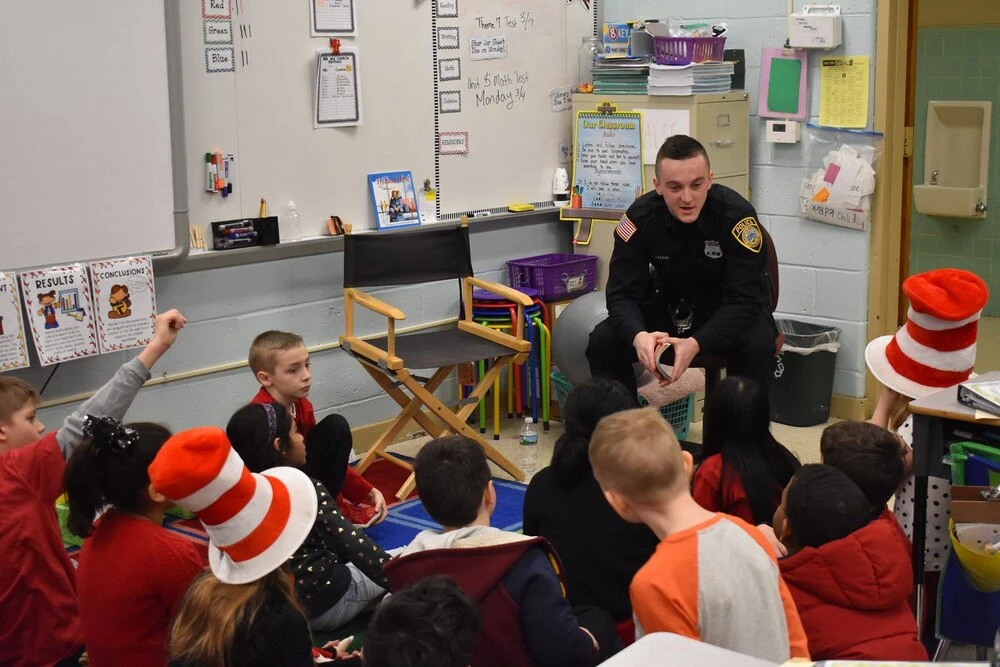 a police officer answering questions from children with raised hands
