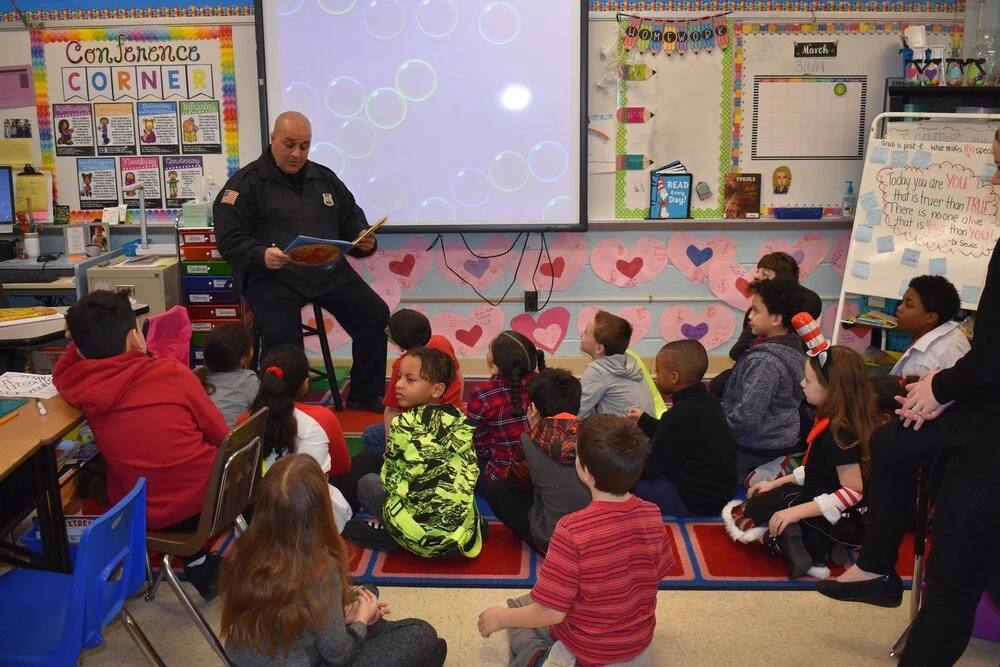 a police officer reads a book to  children
