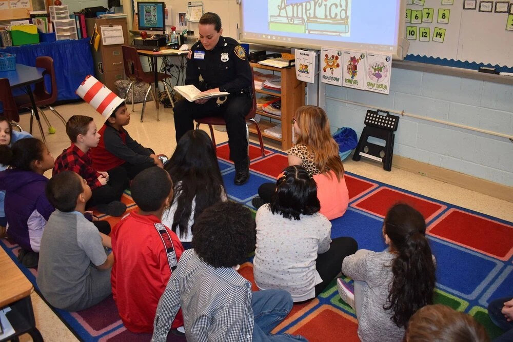 a police officer reads a book to  children