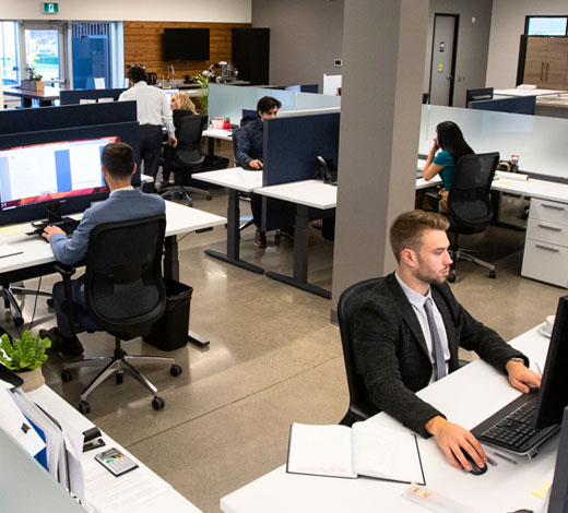 Modern open-concept office with Urban Solutions team members collaborating and working at their desks, reflecting a dynamic and professional workplace environment.