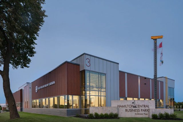 xterior view of a modern industrial building at Hamilton Central Business Park with glass entrance, wood-toned panels, and landscaped grounds at dusk.