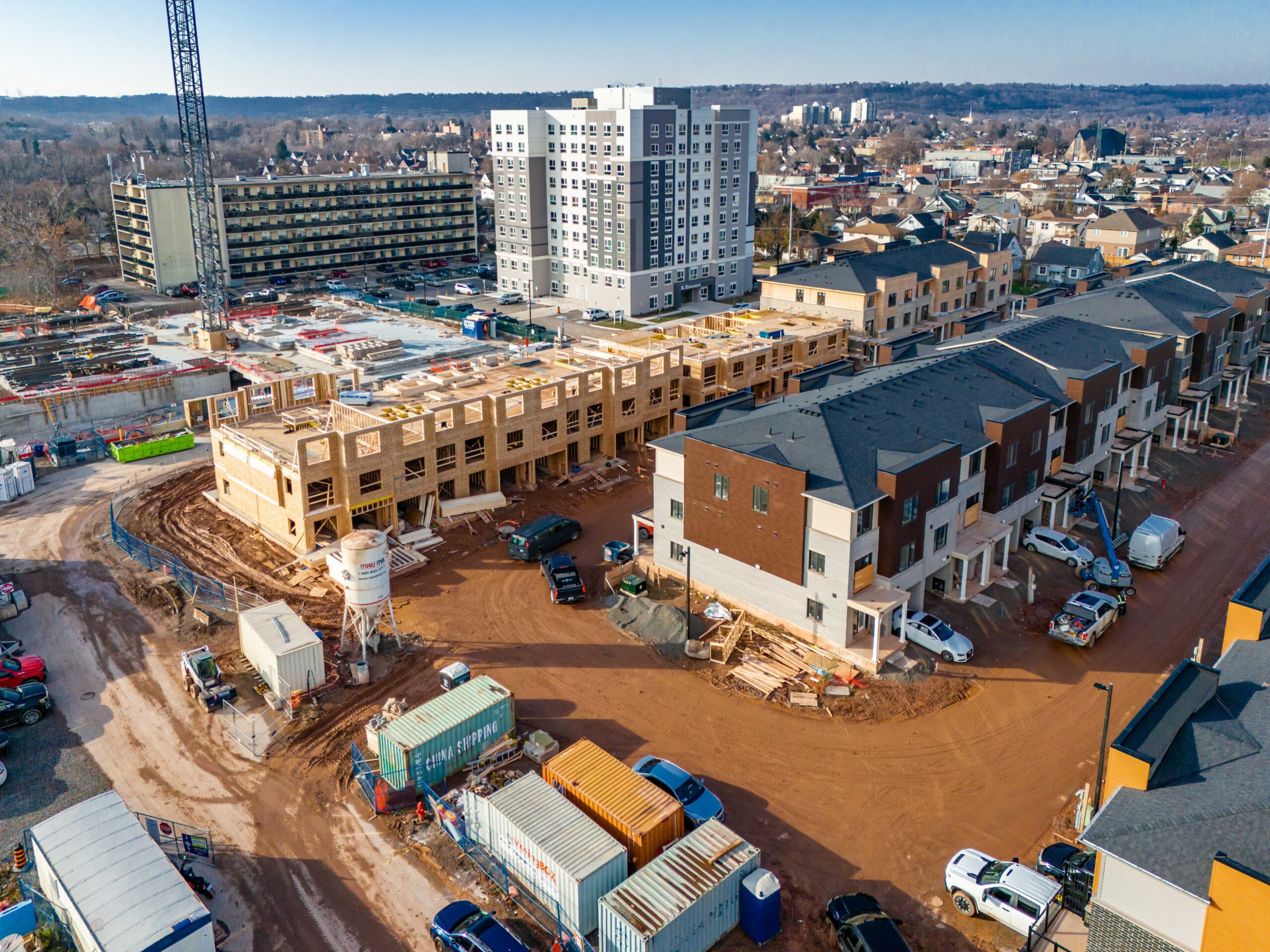 Aerial view of new townhome blocks under construction at the Roxboro Development, with framing, materials, and equipment visible across the site.