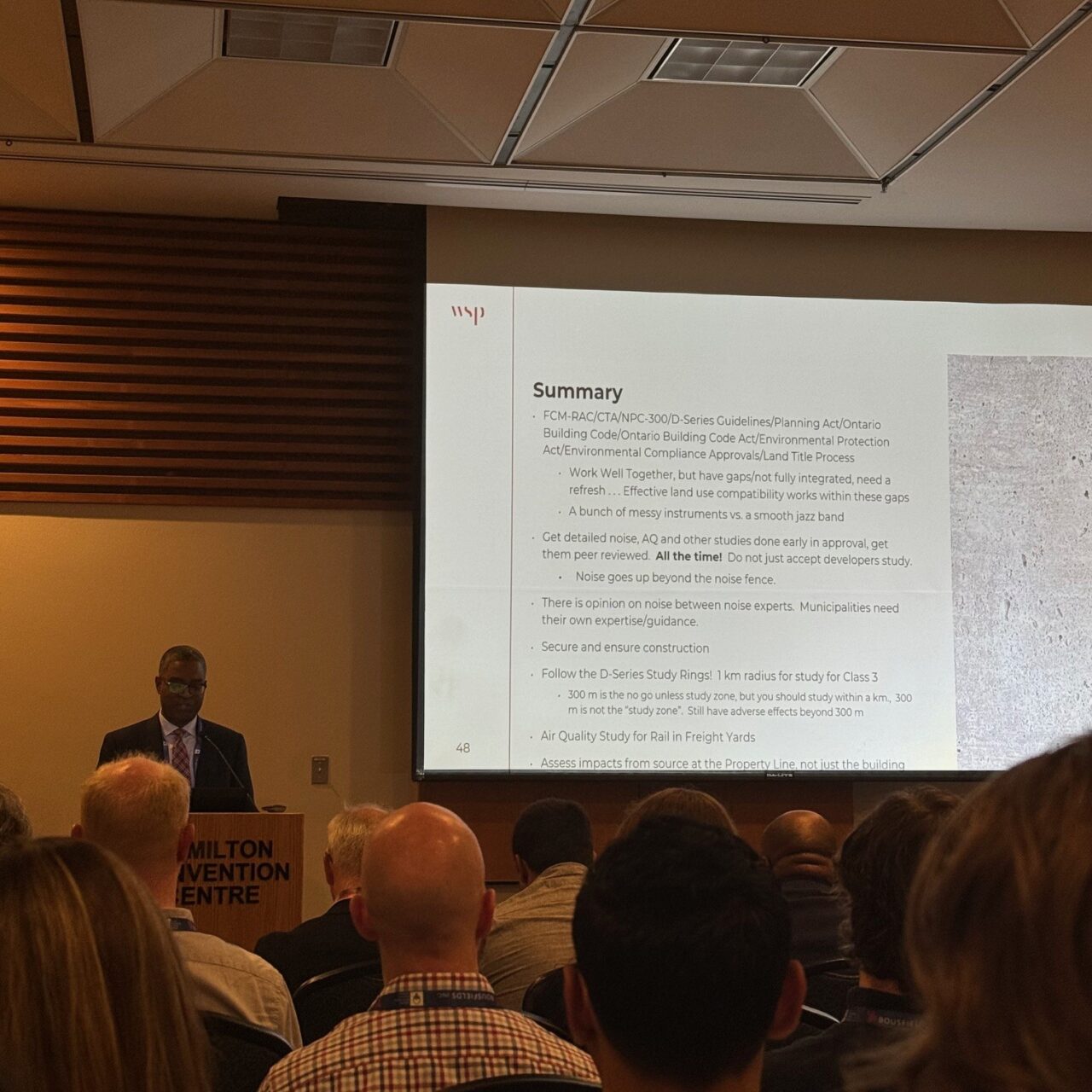 A speaker presents a slide titled “Summary” during a technical session at the OPPI Conference, with attendees seated in rows listening.