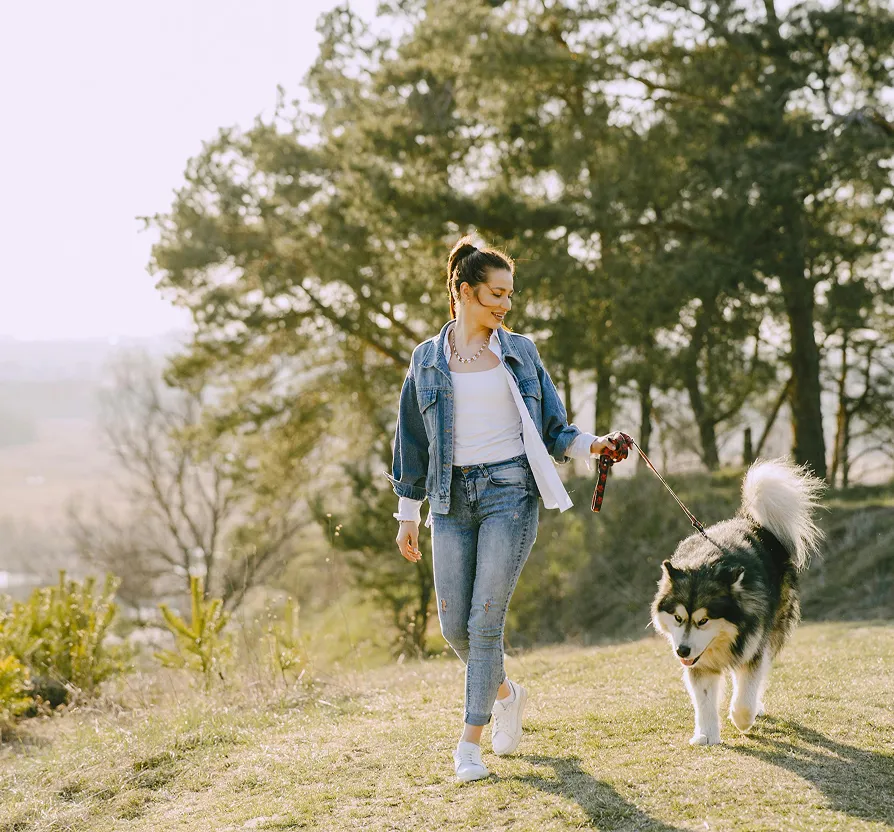 Woman in Great Neck, NY, enjoys optimized health with custom-built, personalized care, walking a dog.