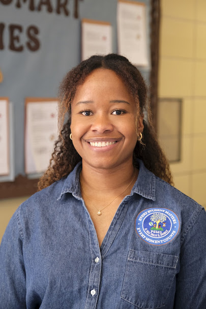 Smiling PS 262 staff member Ms. Duke in school hallway