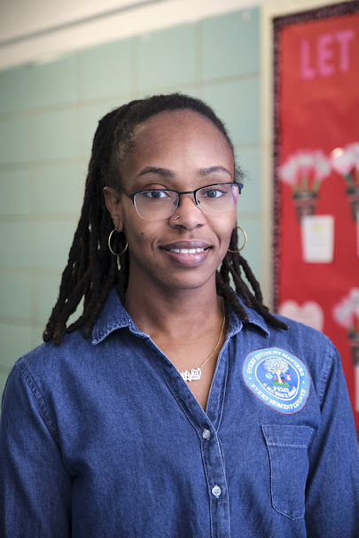 Ms. Jarvis smiling in school hallway wearing staff shirt