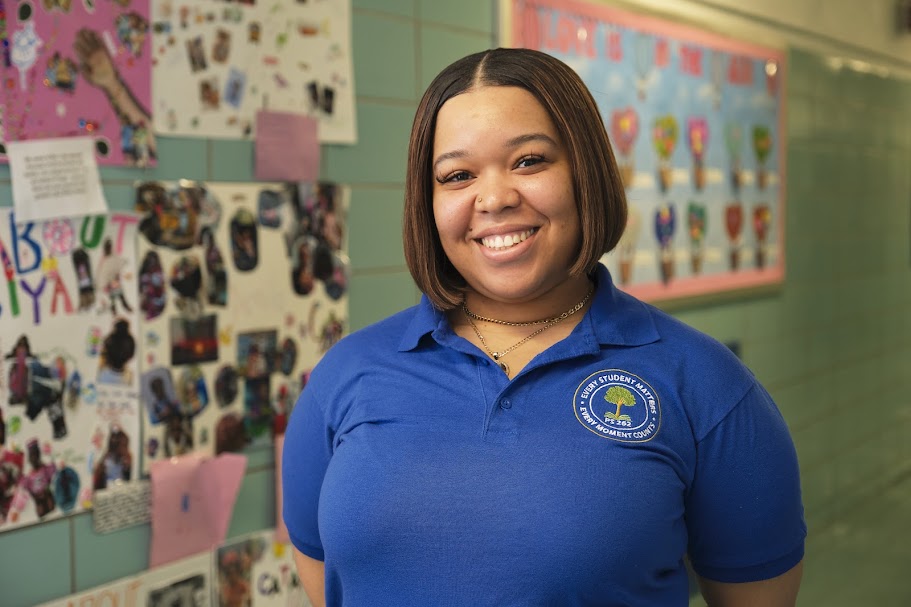 Ms. McLaughlin smiling in school hallway wearing district polo shirt